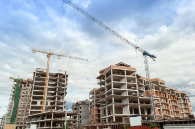 Mavi gökyüzünün arka planında yapım aşamasındaki çok katlı bir bina ve vinç.