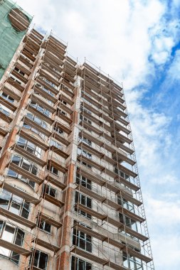 Mavi gökyüzünün arka planında yapım aşamasındaki çok katlı bir bina ve vinç.