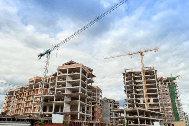 Mavi gökyüzünün arka planında yapım aşamasındaki çok katlı bir bina ve vinç.