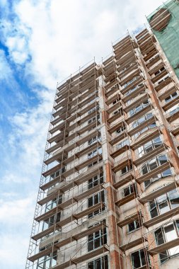 Mavi gökyüzünün arka planında yapım aşamasındaki çok katlı bir bina ve vinç.