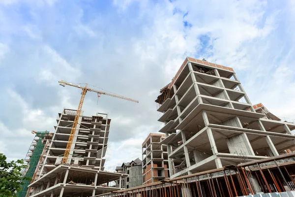 Mavi gökyüzünün arka planında yapım aşamasındaki çok katlı bir bina ve vinç.