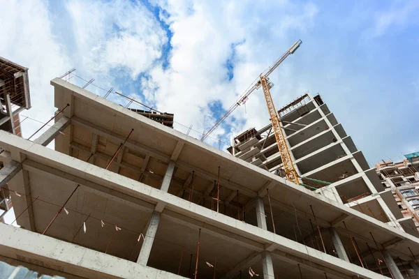 Mavi gökyüzünün arka planında yapım aşamasındaki çok katlı bir bina ve vinç.