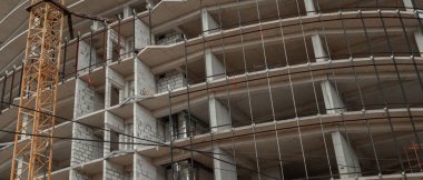 Mavi gökyüzünün arka planında inşaat halindeki çok katlı bir bina ve vinç manzarası