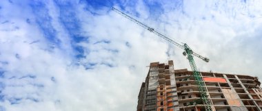 Mavi gökyüzünün arka planında inşaat halindeki çok katlı bir bina ve vinç manzarası