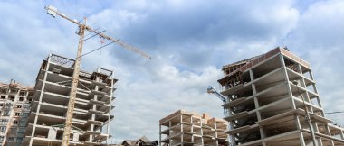 Mavi gökyüzünün arka planında inşaat halindeki çok katlı bir bina ve vinç manzarası