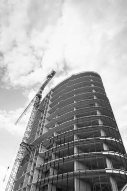 Mavi gökyüzünün arka planında yapım aşamasında olan çok katlı bir binanın siyah beyaz fotoğrafı.