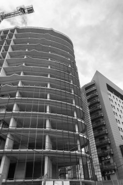 Mavi gökyüzünün arka planında yapım aşamasında olan çok katlı bir binanın siyah beyaz fotoğrafı.