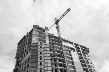 Mavi gökyüzünün arka planında yapım aşamasında olan çok katlı bir binanın siyah beyaz fotoğrafı.