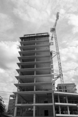 Mavi gökyüzünün arka planında yapım aşamasında olan çok katlı bir binanın siyah beyaz fotoğrafı.