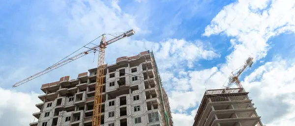 Mavi gökyüzünün arka planında inşaat halindeki çok katlı bir bina ve vinç manzarası