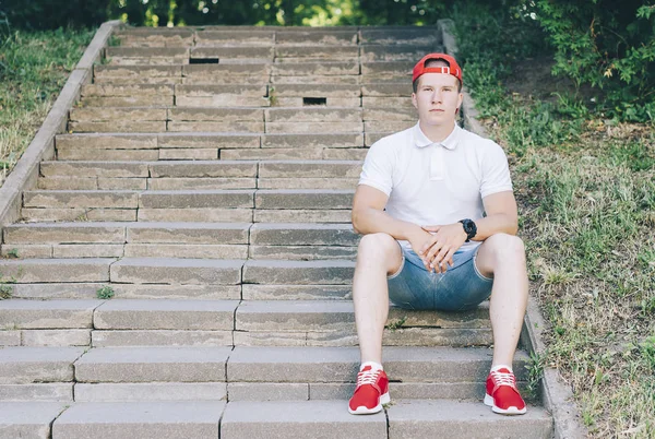 Hombre con gorra sentado en las escaleras —  Fotos de Stock