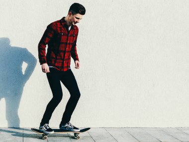 Genç adam kaykaya biniyor. 