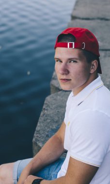 Nehri üzerinde oturan şapkalı adam