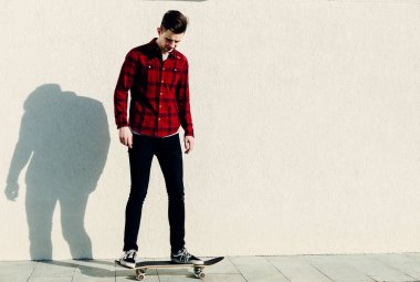 Genç adam kaykaya biniyor. 