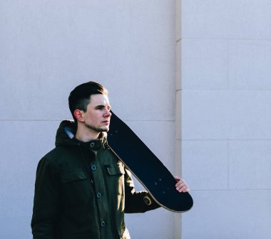 Genç adam kaykaya biniyor. 