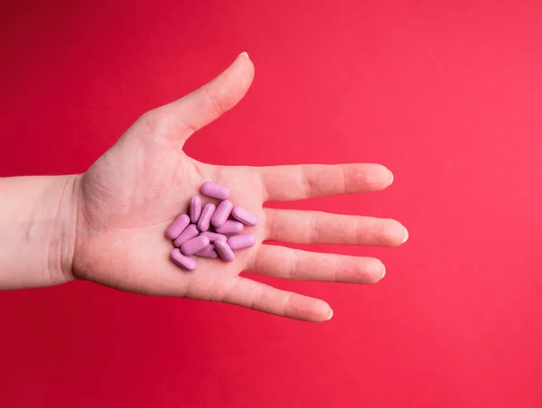 Elinde pembe haplar tutan kadınların eli. Bir elinde pembe haplar olan genç bir kadının fotoğrafı. İlaç hapları. Vitamin hapları. Mide ilacı, ereksiyon, uyku, sindirim, uyuşturucu