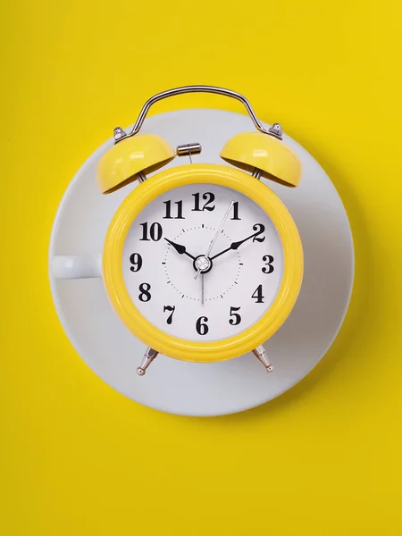 stock image cup of clock. yellow retro alarm clock on yellow  background. Round alarm clock. ten hours ten minutes of the morning time to get up to wake up and have breakfast morning or evening jog to go to work