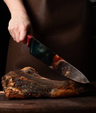 Gemide et kesmek için bıçak, jamon, kurutulmuş et, dana eti. Kuru jambon, Parma jambonu, siyah arka planda bütün bacak izole edilmiş. Kurumuş İtalyan bacağı. Tütsülenmiş biftek. Tahtada kurutulmuş sigara. Et dükkanı