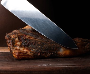 Gemide et kesmek için bıçak, jamon, kurutulmuş et, dana eti. Kuru jambon, Parma jambonu, siyah arka planda bütün bacak izole edilmiş. Kurumuş İtalyan bacağı. Tütsülenmiş biftek. Tahtada kurutulmuş sigara. Et dükkanı