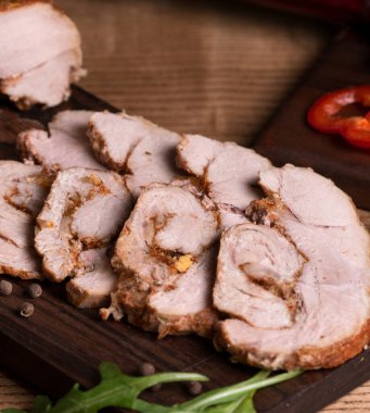 Gri ahşap bir masada, tahta bir tahtanın üzerinde sebzeli ve otlu rulo köfte. Pişmiş et. Metin için boşluk olan üst görünüm. Dikey oryantasyon. Kırsal tarzda. Organik çiftlikten doğal ürün..