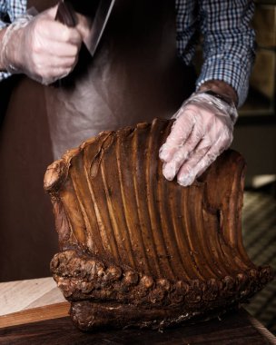 Şef füme bir kaburgayı baltayla keser. Tütsülenmiş domuz pirzolası. Tahtada et şarküteri var. Kuru kaburga. Et dükkanı. Şef et kesti.