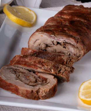 Gri ahşap bir masada, tahta bir tahtanın üzerinde sebzeli ve otlu rulo köfte. Pişmiş et. Metin için boşluk olan üst görünüm. Dikey oryantasyon. Kırsal tarzda. Organik çiftlikten doğal ürün..