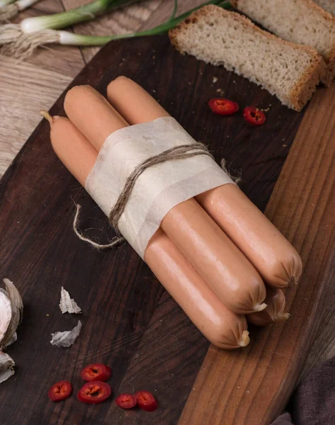 Sliced boiled ham sausage. sandwich of rye bread with boiled sausage and vegetables on a rustic wooden background