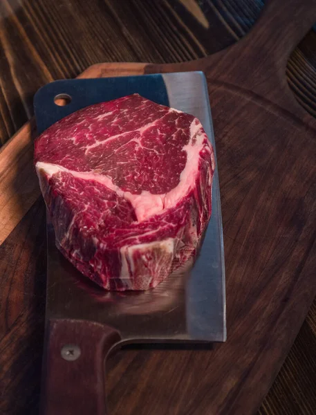 Rib eye steak on an ax. Raw Black Angus Beef Steak . Raw beef steak beef steak on a wooden board with an ax.