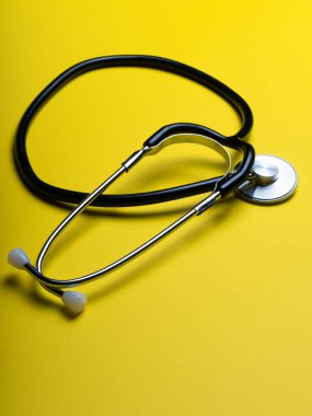 Doktor teşhis koronavirüsü hastalığı için siyah stetoskop, sarı arka planda fotokopi alanı olan sağlık için tıbbi araç. Phonendoskop ve siyah maskeli mor arka plan. Tıbbi araçlar