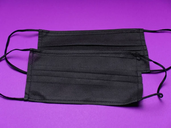COVID-19. Yığının üzerinde yüz maskeleri var. Salgın geçmişi. Karantina geçmişi. Korunmak için tıbbi maskeler. Tehlikeli bir virüs. Mor arka planda maske. Test için maske. Boşluğu kopyala