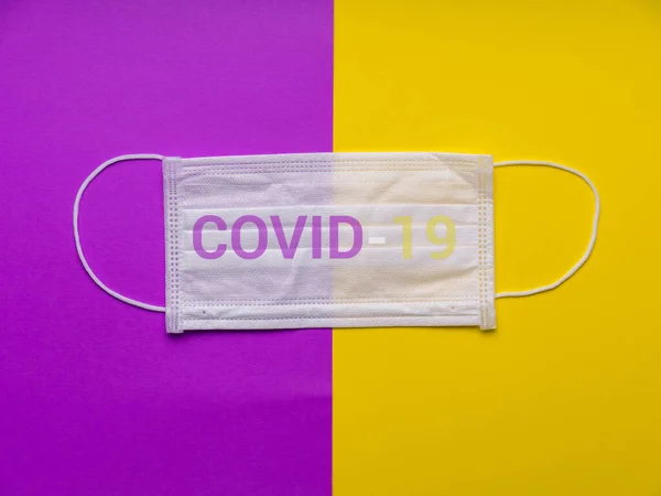 Surgical mask with rubber ear straps. Typical 3-ply surgical mask to cover the mouth and nose. Procedure mask from bacteria. Protection concept. Covid 19  masks. Coronavirus. mask on yellow background