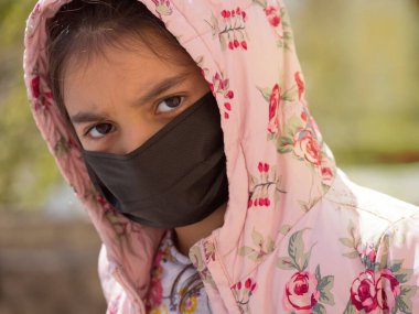 Tıbbi maskeli bir kız. Karantinaya alın. Covid-19. Yalıtım. Coronavirus kilitlenirken evinin yakınında duran tatlı küçük kız. Üzgün çocuk yalnız zaman geçiriyor, çocuk kendini yalnız hissediyor. yalnızlık