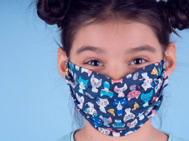 Renkli maskeli komik kız. Heyecan ve cazibe konsepti. Portreyi kapat. Stüdyo görüntüsü mavi arkaplanda. Aptalca somurtmalar komik çılgın jestler. Komik bir ifade. Covid-19. Küçük doktor. Evde kal. Kendine dikkat et.