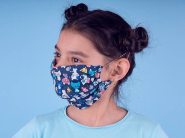 Renkli maskeli komik kız. Heyecan ve cazibe konsepti. Portreyi kapat. Stüdyo görüntüsü mavi arkaplanda. Aptalca somurtmalar komik çılgın jestler. Komik bir ifade. Covid-19. Küçük doktor. Evde kal. Kendine dikkat et.