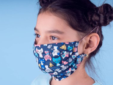 Sarı arka planda renkli maskeli şirin bir kız. Covid-19 'u durdurun. Evde kal. Karantinaya alın. Coronavirus. Kız doktoru oynuyor. Eğitim ve işgal konsepti. Kendinde kal. Alan arkaplanını kopyala