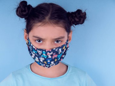 Sarı arka planda renkli maskeli şirin bir kız. Covid-19 'u durdurun. Evde kal. Karantinaya alın. Coronavirus. Kız doktoru oynuyor. Eğitim ve işgal konsepti. Kendinde kal. Alan arkaplanını kopyala