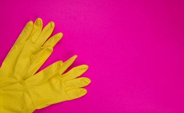 Pembe arka planda temizlik için lastik eldiven, ıslahevi konsepti. Ticari temizlik şirketi. Renkli lastik koruyucu eldiven giyen işçi elleri. Genel ya da düzenli temizlik. 