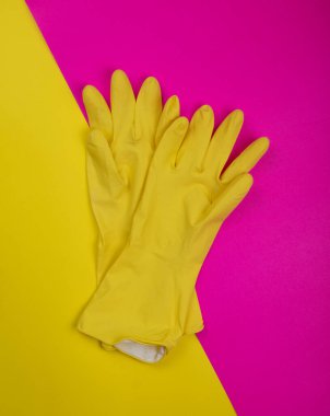 Pembe arka planda temizlik için lastik eldiven, ıslahevi konsepti. Ticari temizlik şirketi. Renkli lastik koruyucu eldiven giyen işçi elleri. Genel ya da düzenli temizlik. 