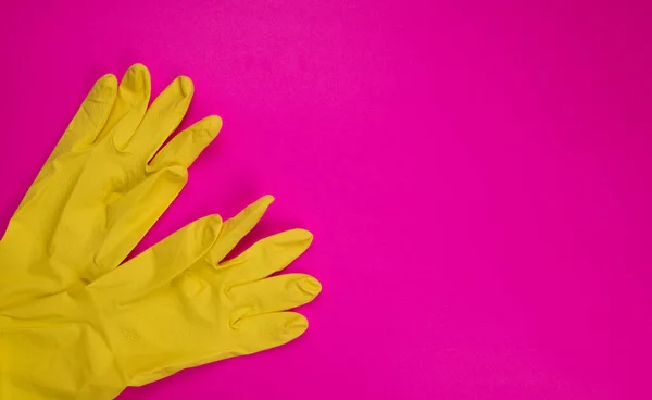 color rubber gloves for cleaning on pink background, workhouse concept. Commercial cleaning company. Employee hands in color rubber protective glove. General or regular cleanup.