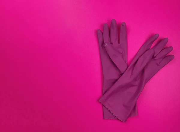 color rubber gloves for cleaning on pink background, workhouse concept. Commercial cleaning company. Employee hands in color rubber protective glove. General or regular cleanup.