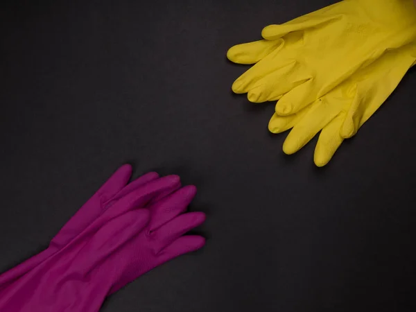 color rubber gloves for cleaning on black background, workhouse concept. Commercial cleaning company. Employee hands in color rubber protective glove. General or regular cleanup.