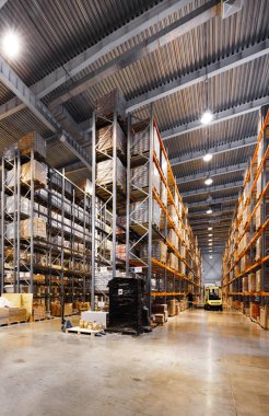 Büyük uzun depo rafları ve yığınla mal.
