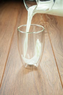 Tahta bir masanın üzerindeki bir sürahide bulunan sütten kahvaltı sütü..