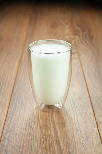 Un vaso lleno de leche para desayunar en una mesa de madera salpicaduras de leche . —  Fotos de Stock