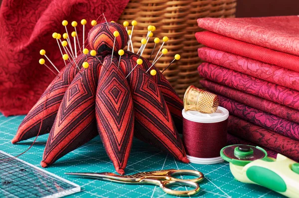 Набор красных тканей и швейных инструментов на коврике — стоковое фото