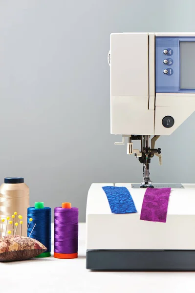 Bobinas de hilos junto a la máquina de coser sobre fondo gris — Foto de Stock