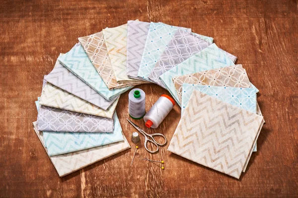 Conjunto de tecidos pastel dispostos em círculo e ferramentas de costura no centro — Fotografia de Stock