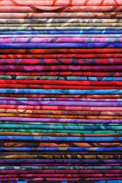 Montón de coloridos tejidos batik como una vibrante imagen de fondo — Foto de Stock