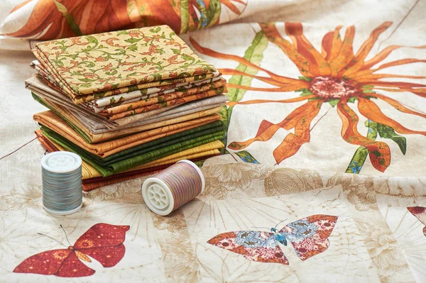 Σωρός από κομμάτια quilting υφάσματα lay σε ύφασμα με λουλούδια και πεταλούδα εικόνες — Φωτογραφία Αρχείου