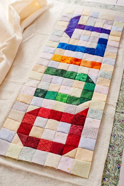 The word quilt sewn from colorful square and triangle pieces of fabric — Stock Photo, Image